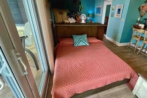 A bedroom with a bed, a nightstand, a window, and a door. - Beachfront-Pool-Fort Myers Beach(our Pool is open) (Fort Myers Beach)