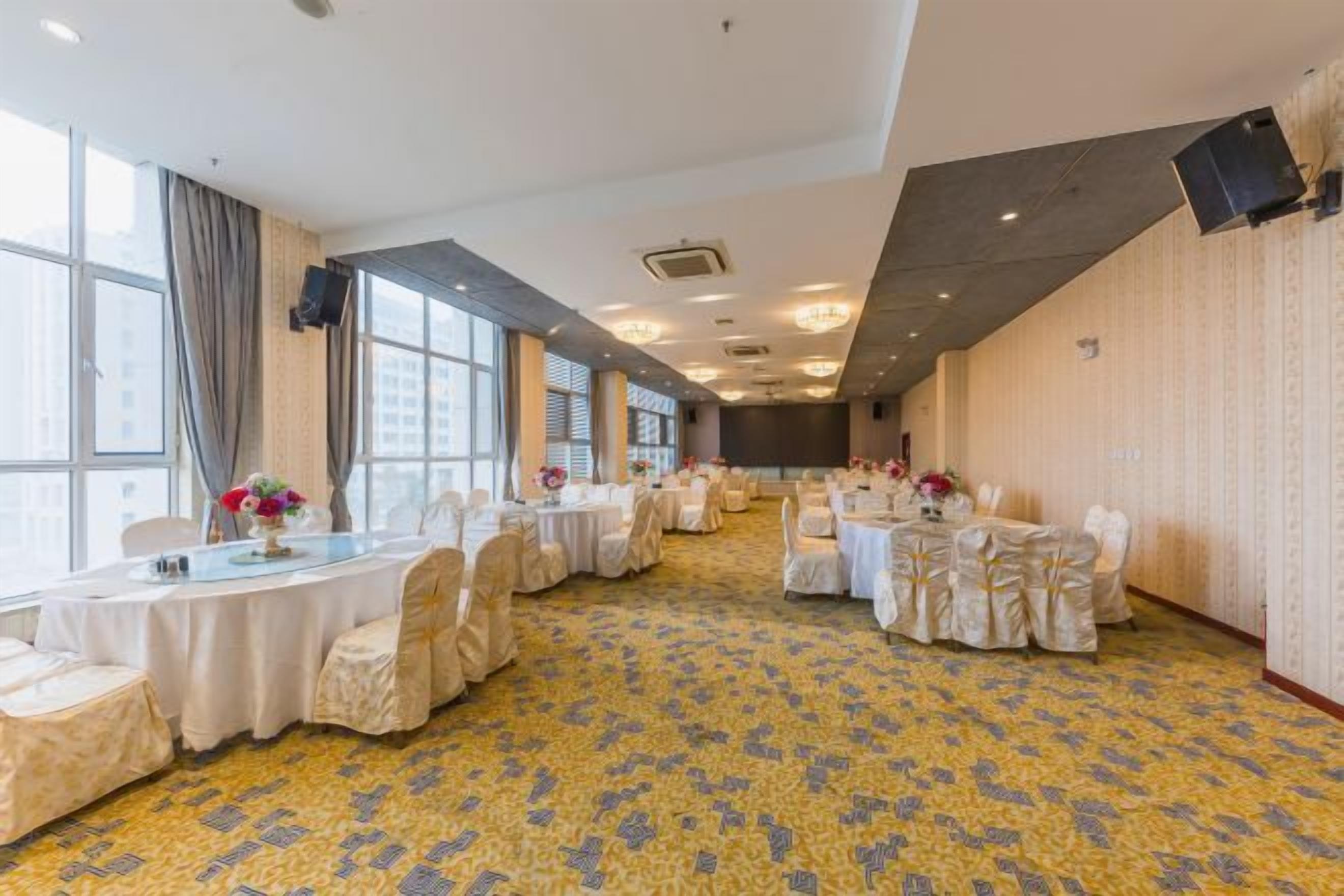 A conference room with round tables, chairs, and a patterned carpet.