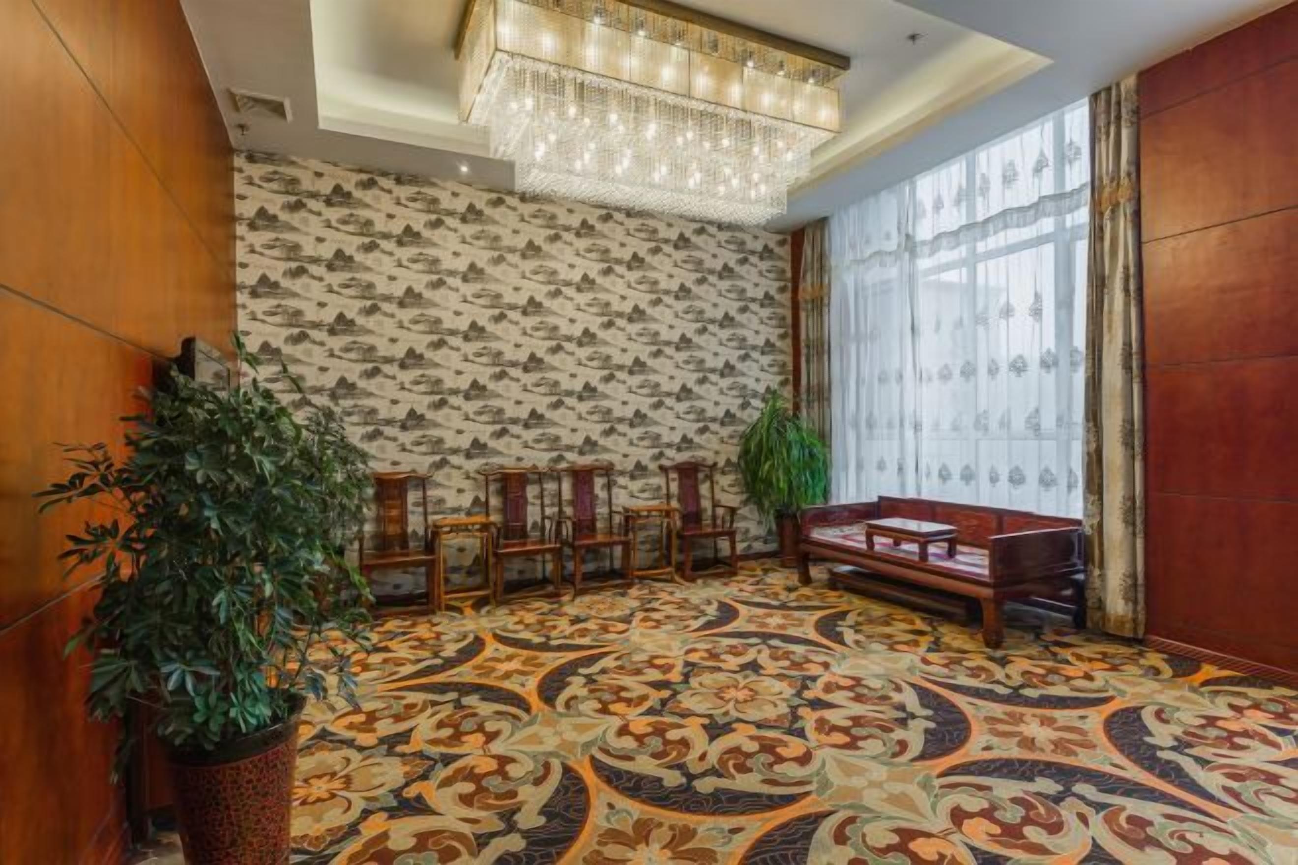 Una habitación con alfombra estampada, un candelabro, un sofá y una planta grande.