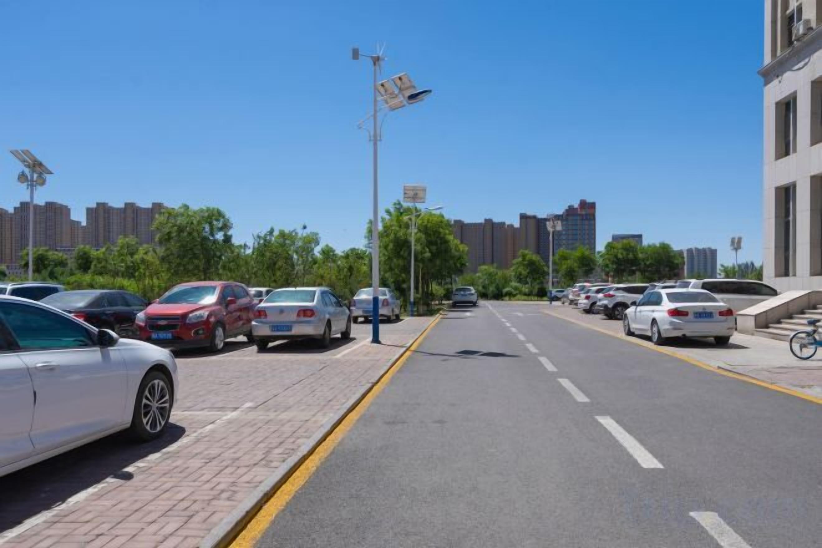 Une rue de la ville avec des voitures garées, un ciel dégagé et des bâtiments en arrière-plan.