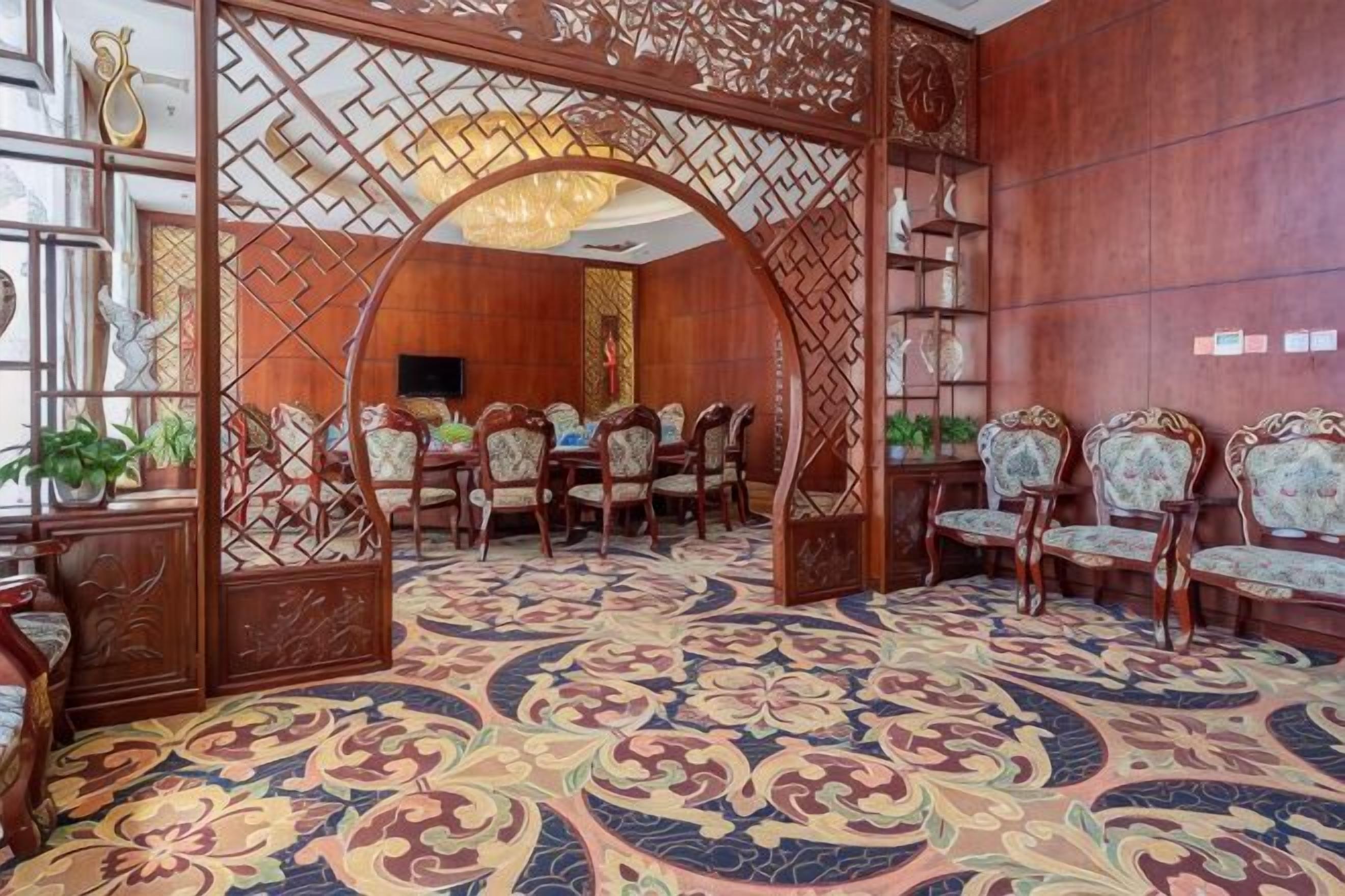 Una habitación tradicional con alfombra estampada, muebles de madera y un arco decorativo.