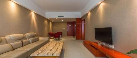A modern living room with a sofa, a coffee table, red chairs, a TV, and a red accent wall.