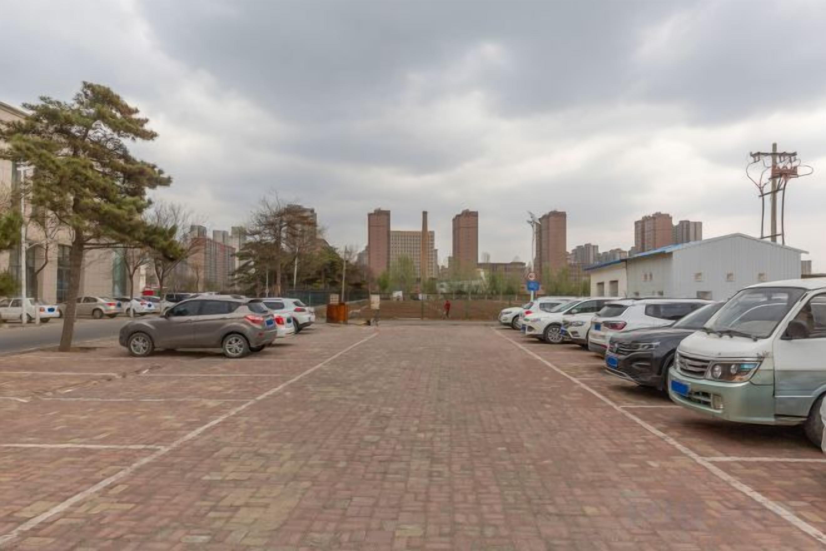 Un parking avec plusieurs voitures et un revêtement de sol en briques.