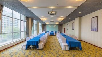 Uma sala de conferências com uma mesa comprida, cadeiras e piso coberto de carpete.