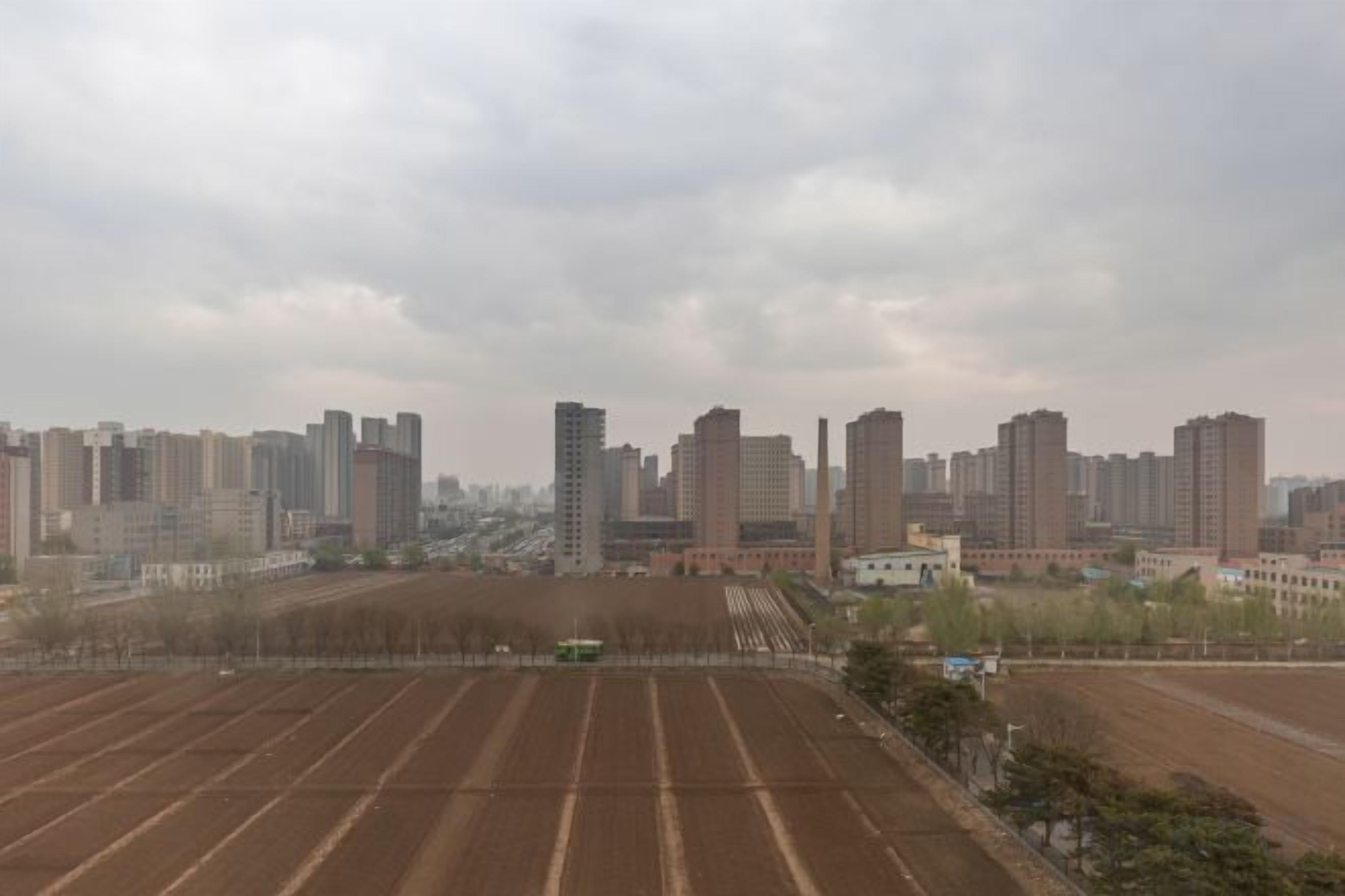 A cityscape with high-rise buildings and a large open field.