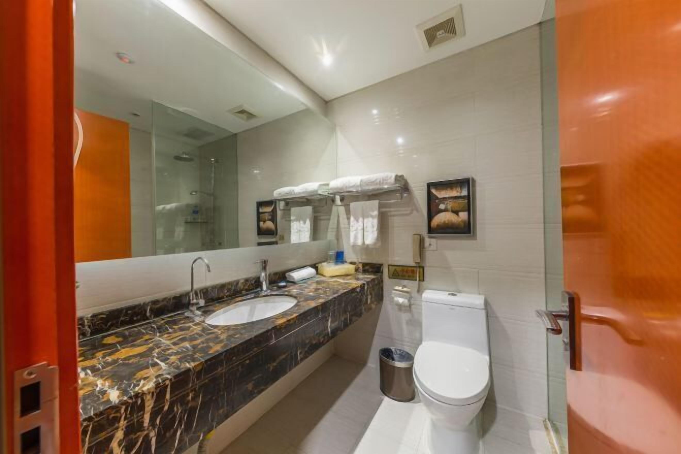 Un baño moderno con lavamanos de mármol, inodoro y cabina de ducha de vidrio.