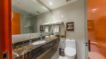 Un baño moderno con lavamanos de mármol, inodoro y cabina de ducha de vidrio.