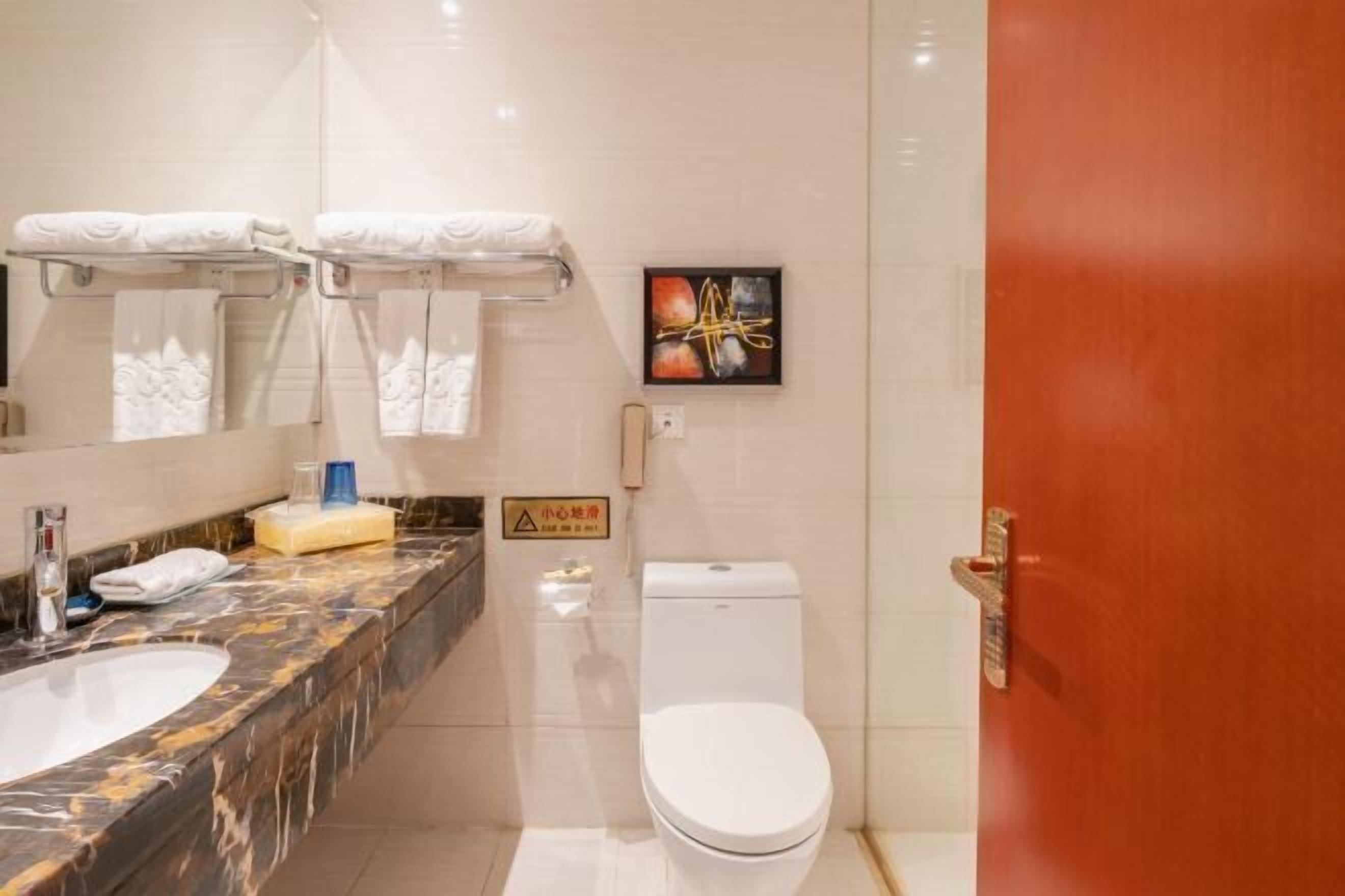 Un baño con encimera de mármol, lavamanos blanco, inodoro y zona de ducha.