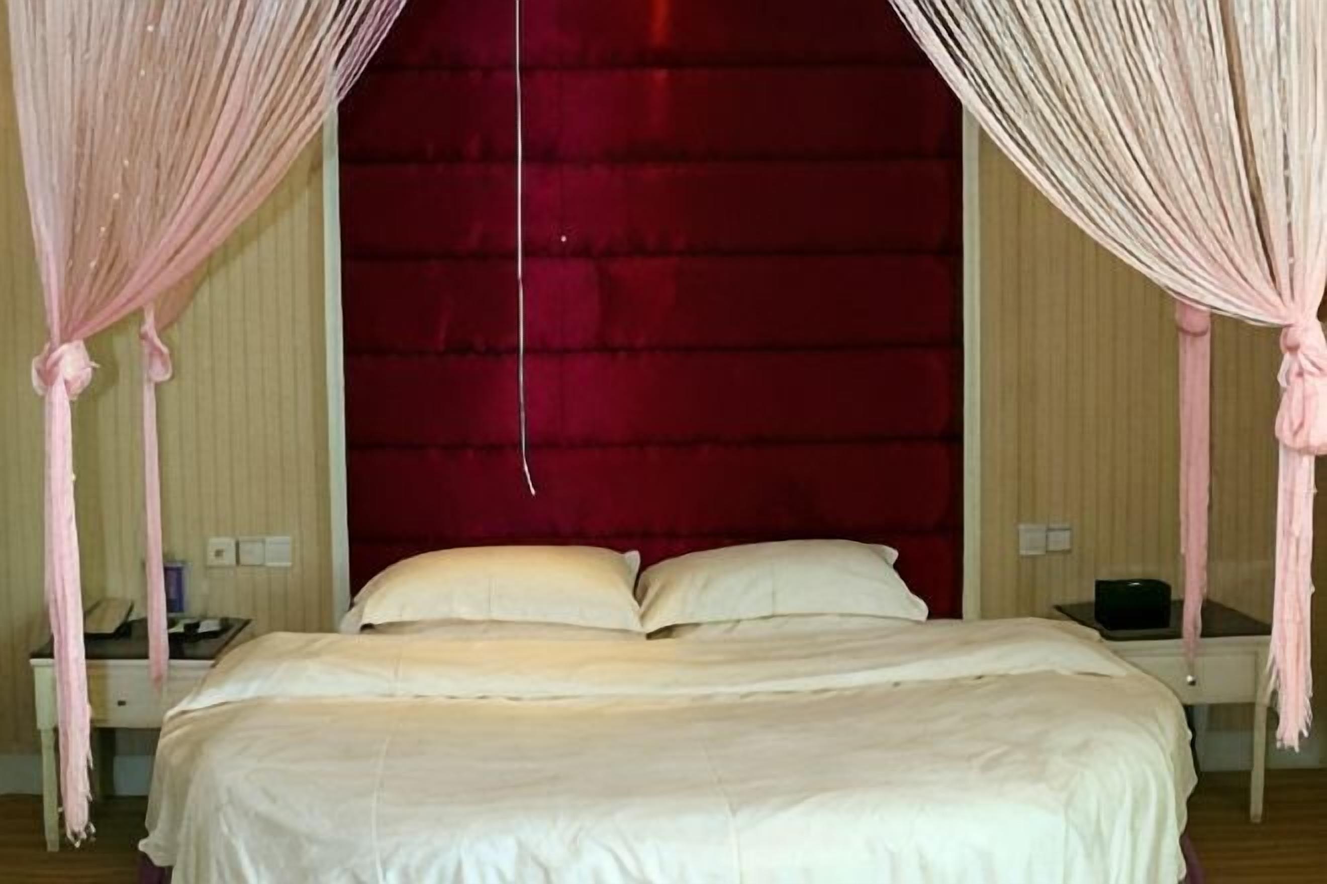 A bed with a canopy, a nightstand, and a red headboard.