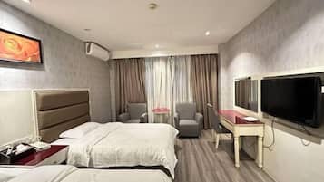 Habitación de hotel con dos camas, un escritorio, una silla, un televisor y una ventana con cortinas.