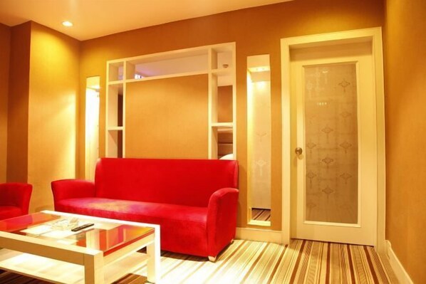 A room with a red sofa, a white coffee table, and a door with a frosted glass panel.