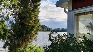 Un chalet au bord du lac, doté d’une grande fenêtre donnant sur l’eau et entouré d’une végétation luxuriante.