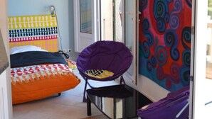 A room with a bed, a chair, a colorful wall, and a door. - Un Balcon sur la Méditerranée 1 (Taglio-Isolaccio)