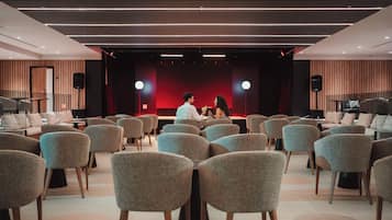 Una sala conferenze con file di sedie rivolte verso un palco dove due persone stanno conversando.