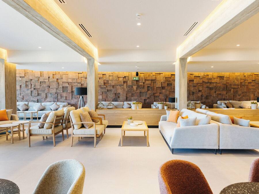 A spacious living area with a modern design, featuring a large sofa, armchairs, a coffee table, and a stone accent wall.