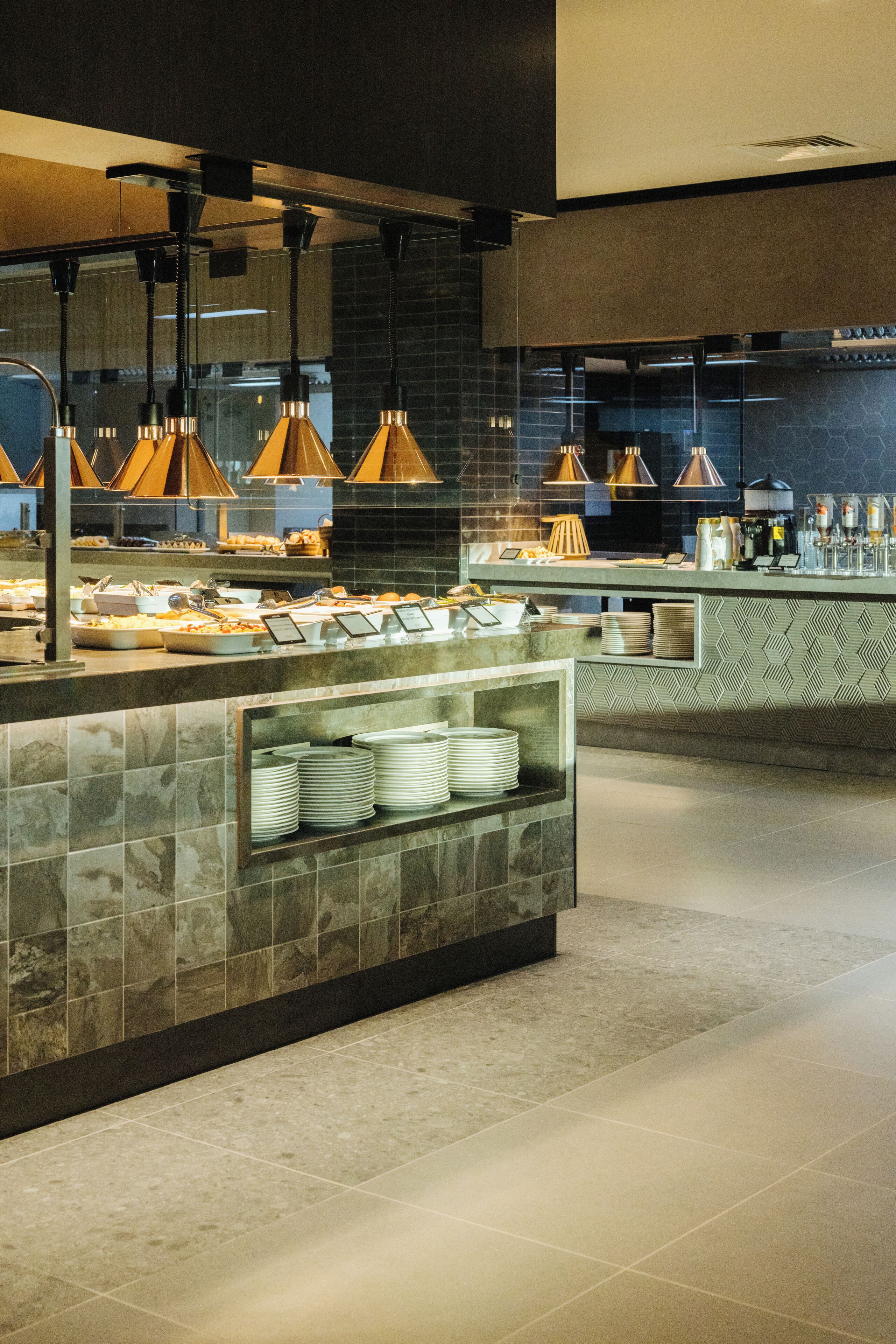 A buffet area with a marble counter, multiple serving stations, and overhead pendant lighting.