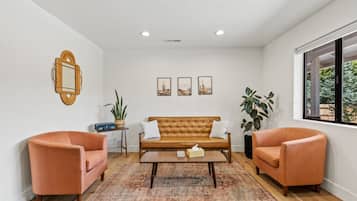 A living room with a brown sofa, two armchairs, a coffee table, and a patterned rug.