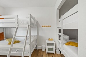 A room with bunk beds, a small bedside table, a wall-mounted shelf, and a trash bin. - The Getaway in Williams  (Williams)