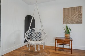 A room with a hanging chair, a small wooden table, and a potted plant. - The Getaway in Williams  (Williams)
