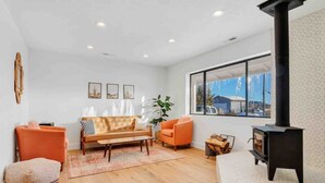 Una sala de estar con sofá, sillones, una mesa de centro, chimenea y un ventanal grande.
