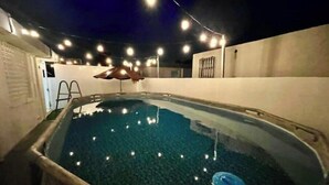 En inomhuspool med klart vatten, omgiven av en vit vägg och en stege.
