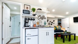 A compact kitchen with white cabinets, a microwave, and a coffee-themed wall. - The Back Yard-Entire Building Downtown Dog Friendly with Yard (Lake Geneva)