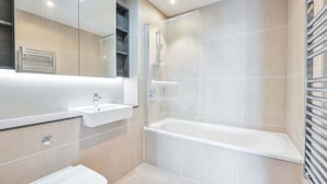 Et moderne badeværelse med vask, spejl, toilet og et brusebadeværelse.