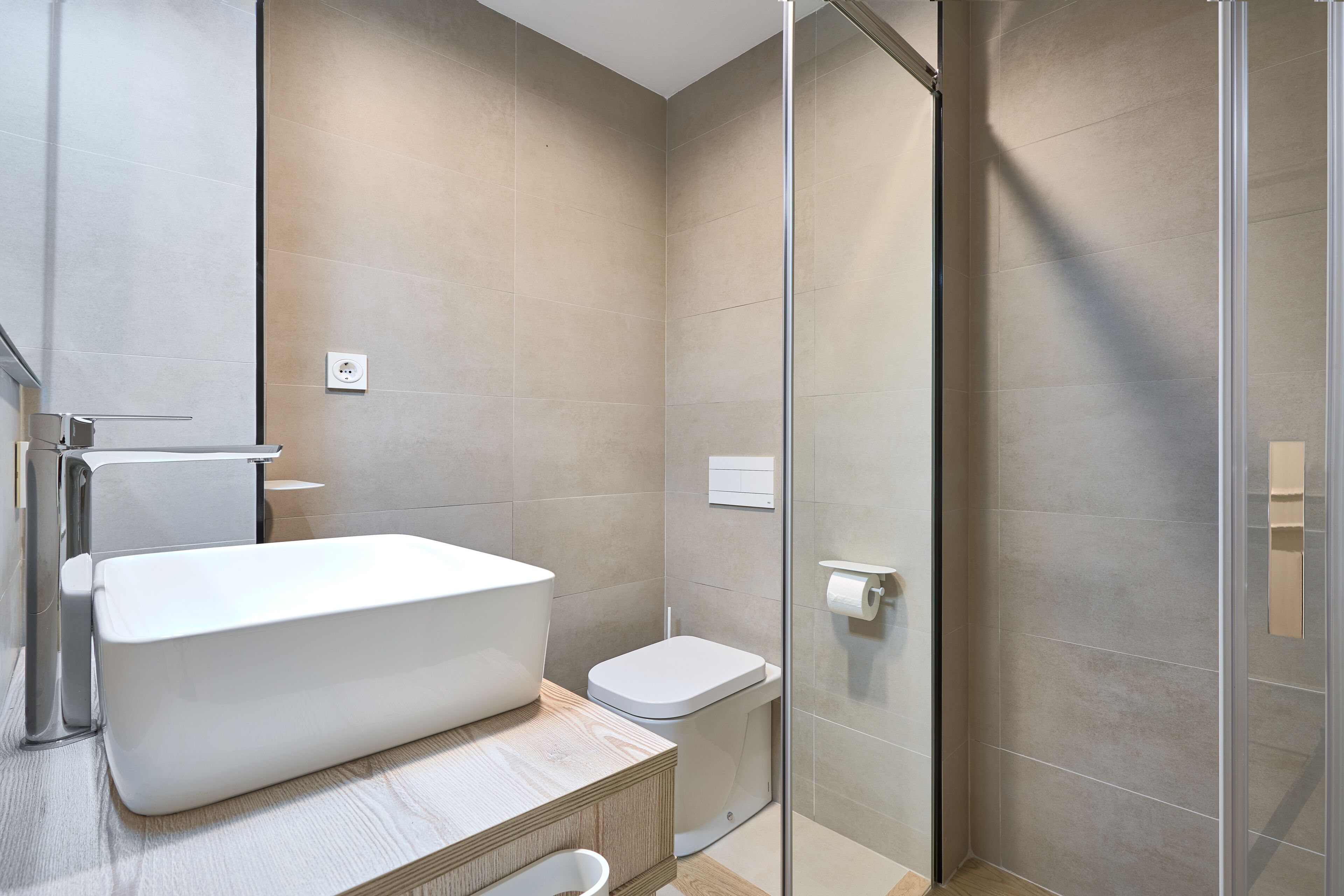 A modern bathroom with a freestanding bathtub, a toilet, and a glass shower enclosure.