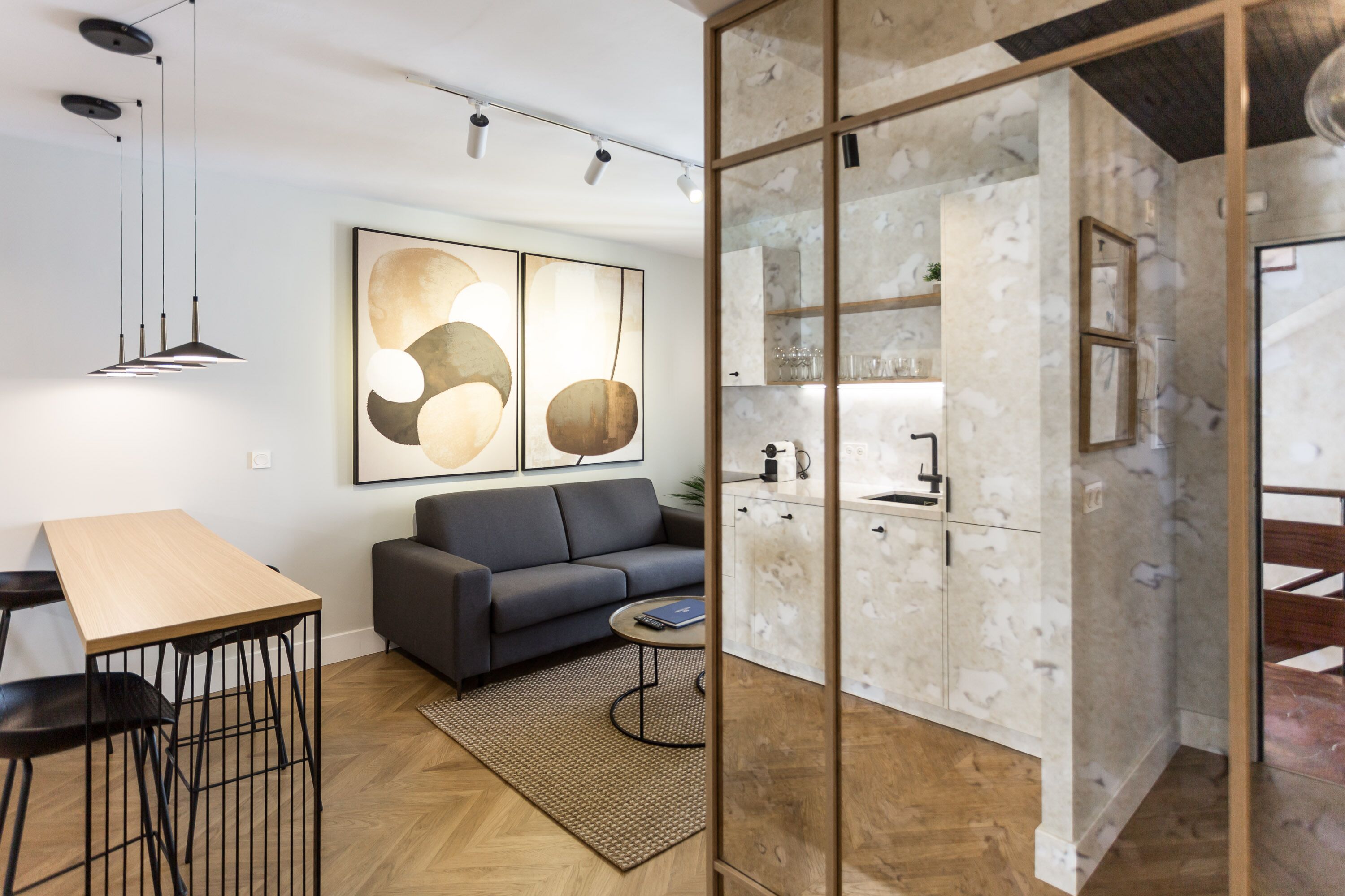 Een moderne woonkamer met een bank, salontafel en hanglampen.