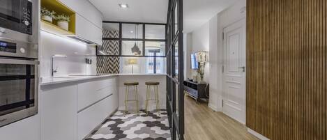 A modern kitchen with a hexagonal tile floor, white cabinetry, and a built-in oven.