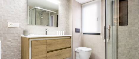 A modern bathroom with a wooden vanity, a glass shower enclosure, and a white toilet.