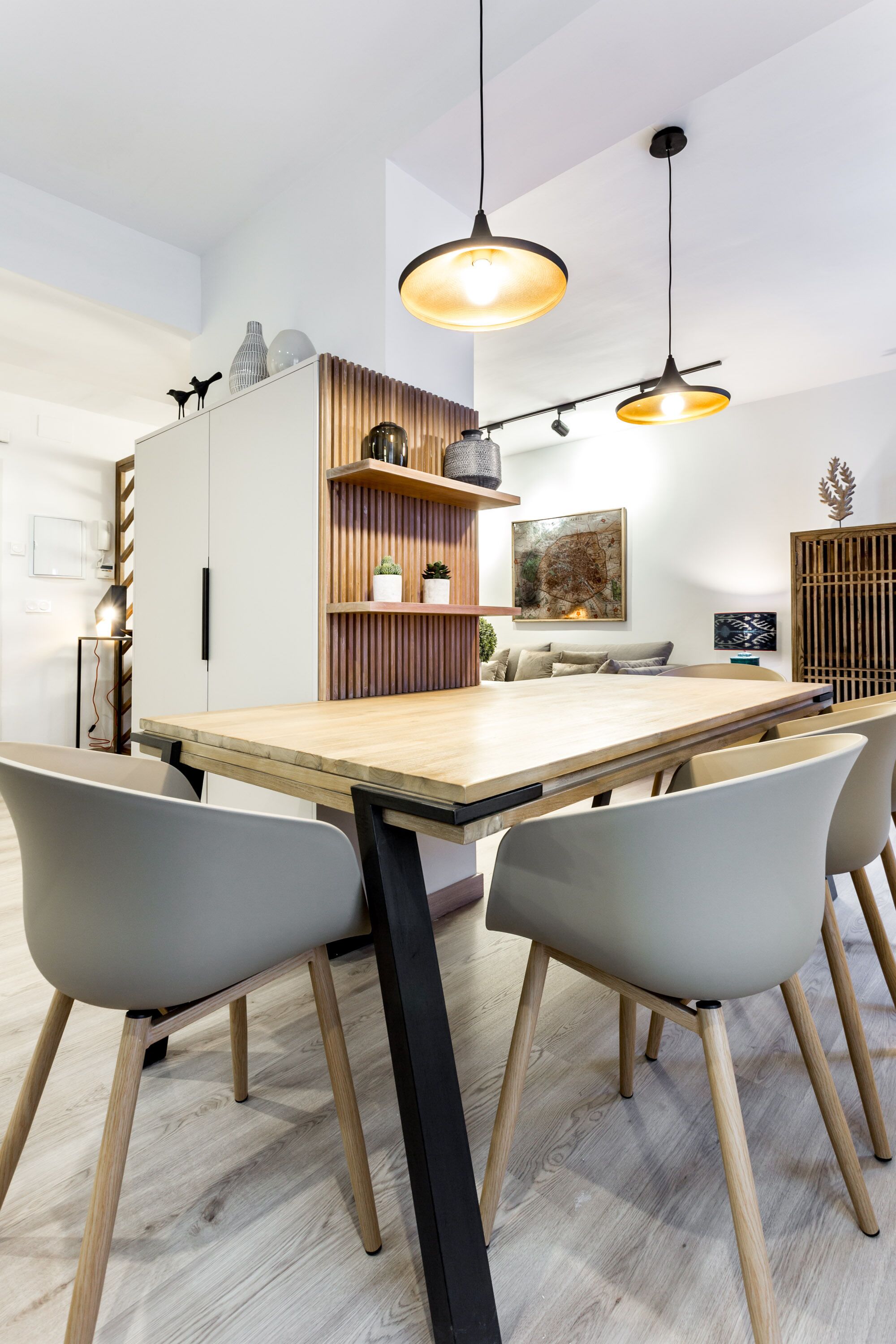 A modern dining area with a wooden table, grey chairs, and pendant lighting.