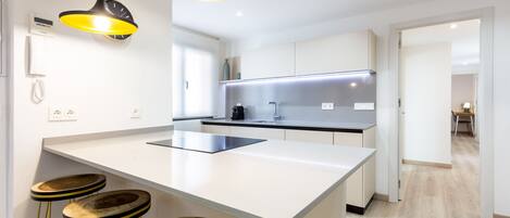 A modern kitchen with a central island, bar stools, pendant lighting, and a view into the adjacent dining area.
