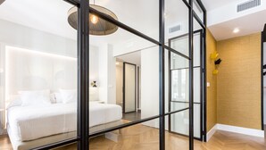 A modern hotel room with a large bed, a glass partition, and a wooden floor. - ELEVEN Apartments Real de la Carretería, by Homing U (Seville)