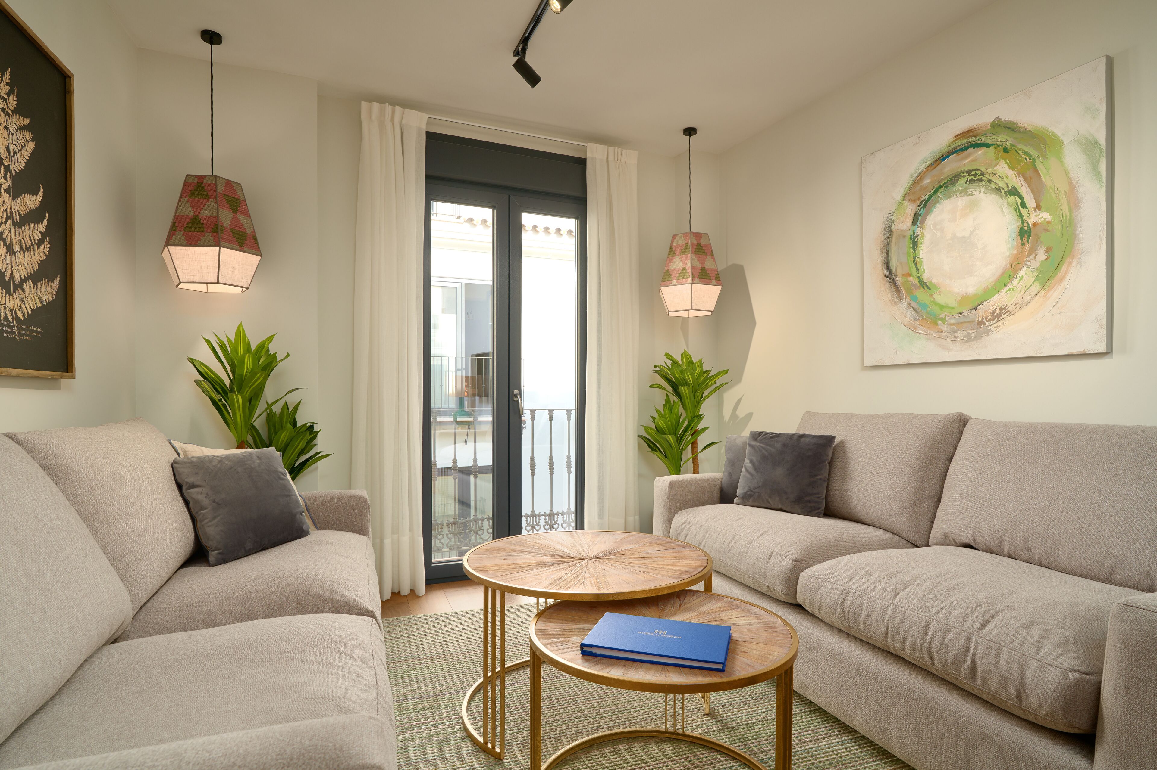 A modern living room with two sofas, a round coffee table, and two pendant lights.