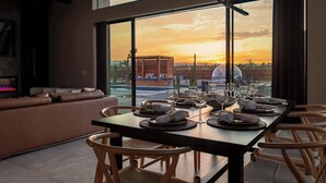 A dining area with a view of a sunset, a sofa, and a fireplace.