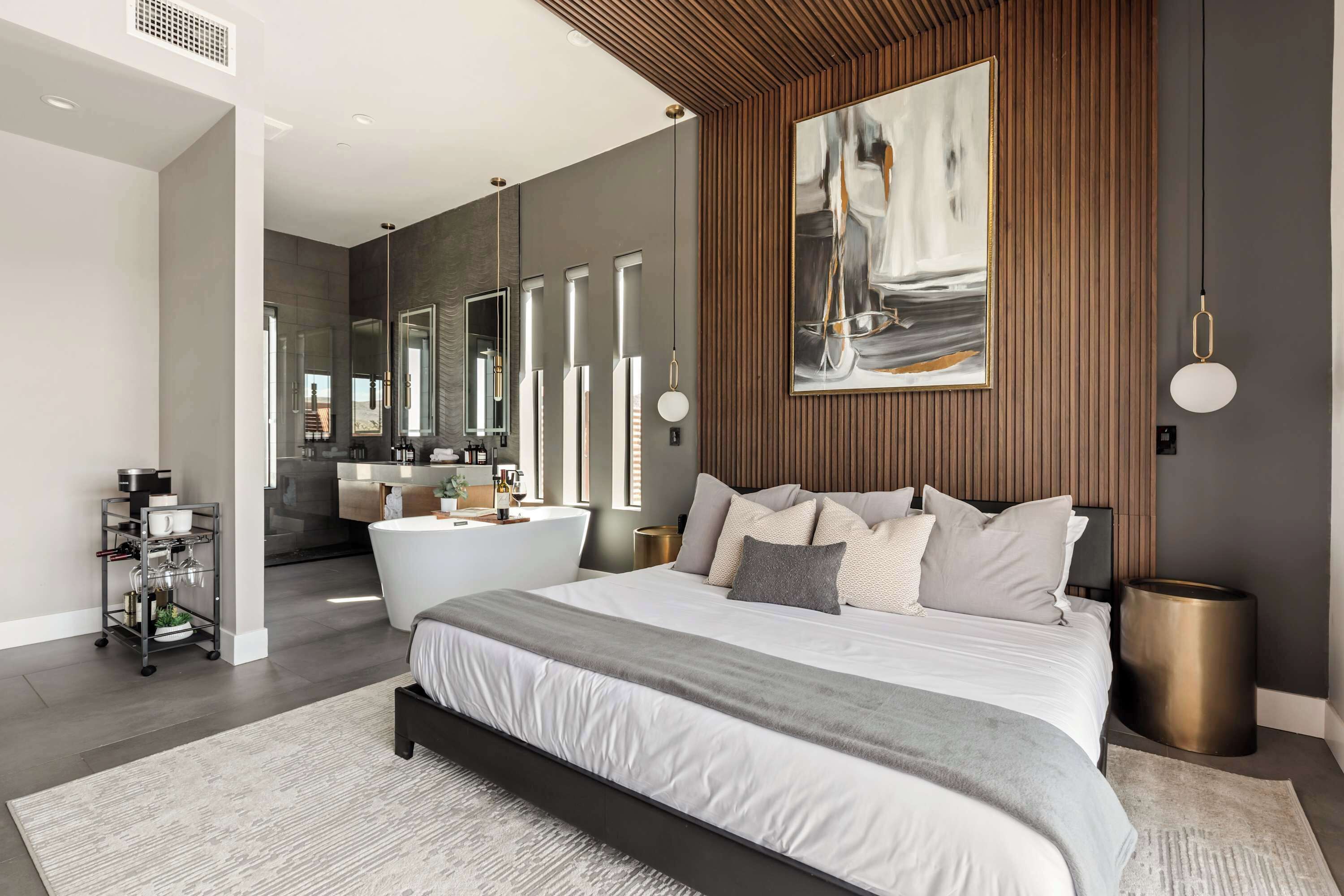 Un dormitorio moderno con una cama grande, un baño con bañera y un comedor con mesa y sillas.