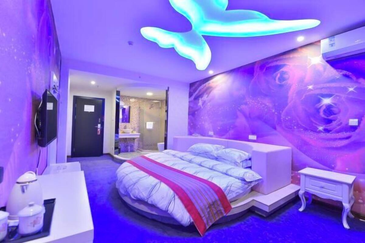 A modern bedroom with a large bed, a nightstand, and a wall mural.