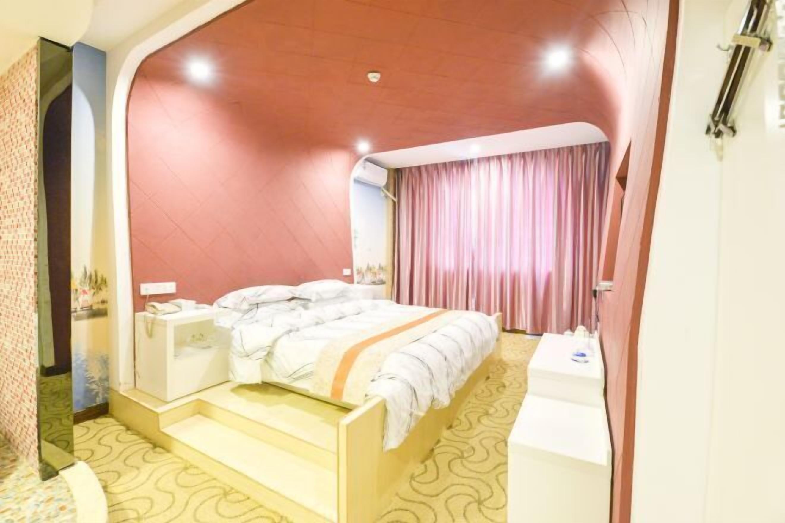 A modern hotel room with a bed, bedside tables, a desk, and a bathroom area.