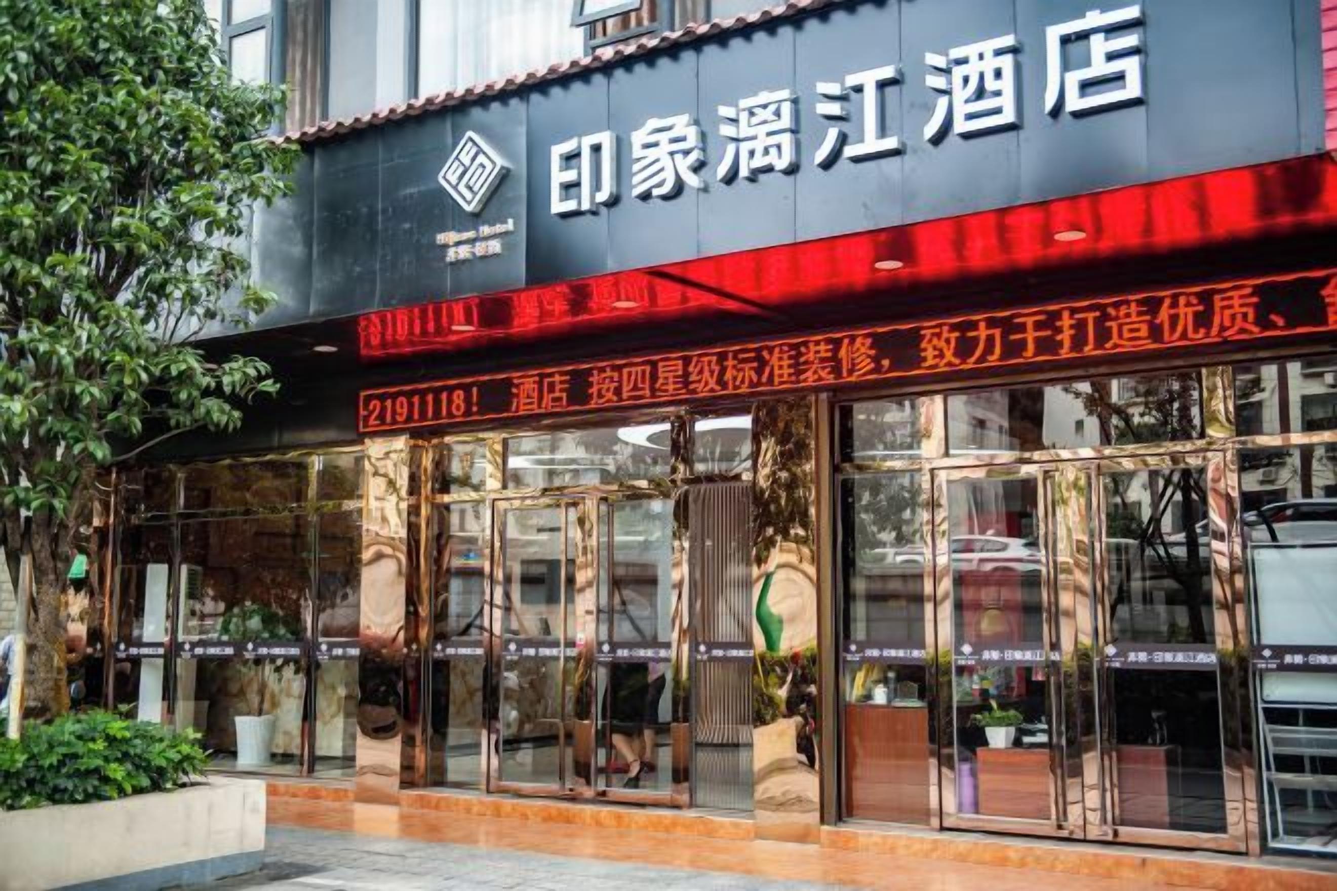 A hotel with a prominent sign, large glass windows, and a tiled entrance.