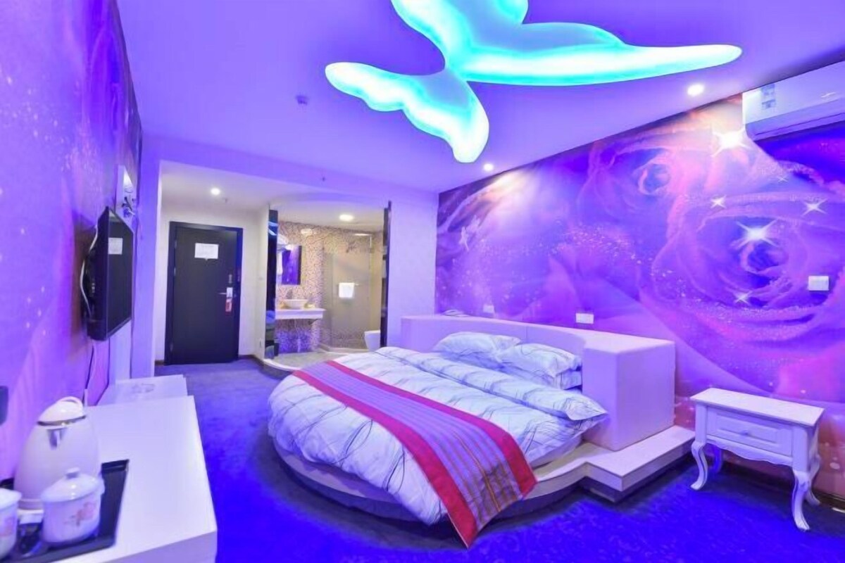 A bedroom with a bed, bedside tables, a wall mural, and a ceiling light fixture.