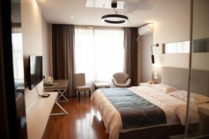 A hotel room with a bed, a desk with a chair, a TV, and a window with curtains. - Impression Lijiang Hotel (Guilin)