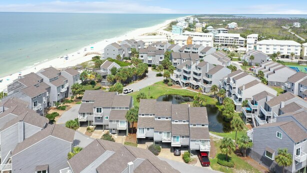 A coastal residential area with multiple-story buildings, a beach, and a clear view of the ocean. - Barrier Dunes 125 - 49 Sand Dollar Shanty (Port St. Joe)