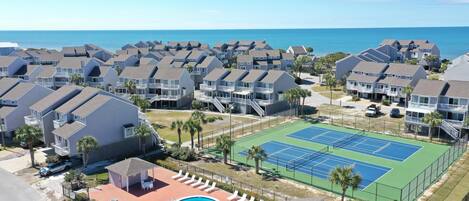 A residential complex with multiple houses, a swimming pool, and a tennis court.