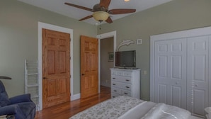 A bedroom with a bed, a ceiling fan, a dresser, and a television. - Camp Palms @ Indian Pass (Port St. Joe)
