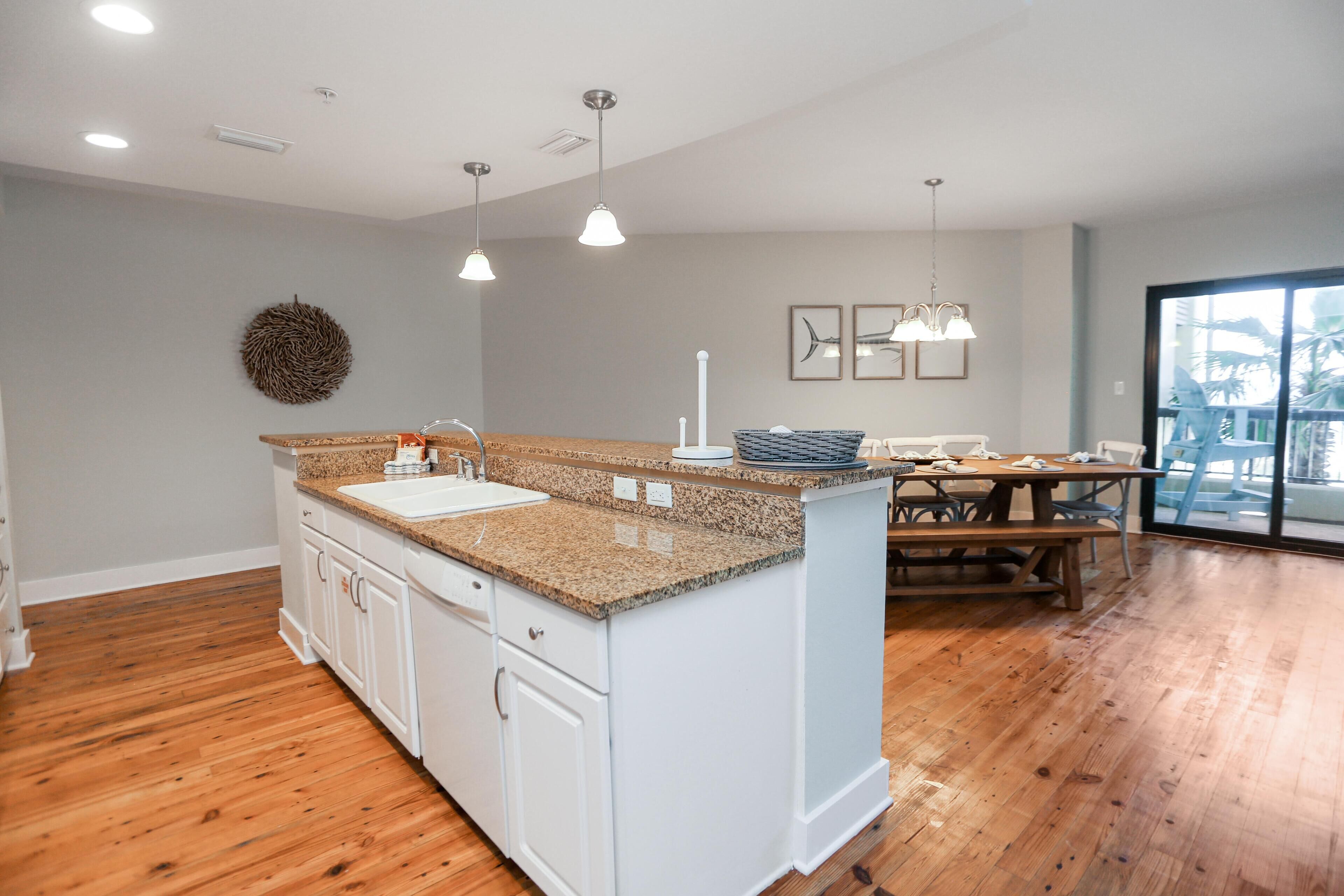 A modern kitchen with white cabinets, granite countertops, and a dining area with a wooden table and benches.