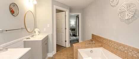 A bathroom with a sink, mirror, and bathtub.
