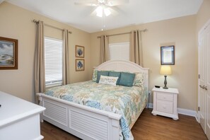 A bedroom with a bed, bedside table, nightstand, and a ceiling fan. - Club at Mexico Beach 2D (Port St. Joe)