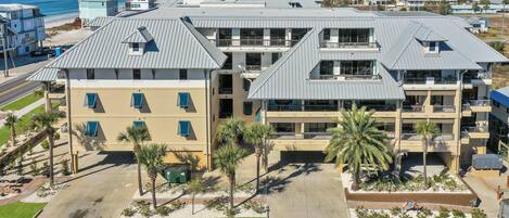 A multi-story hotel with a central courtyard, palm trees, and a view of the beach.