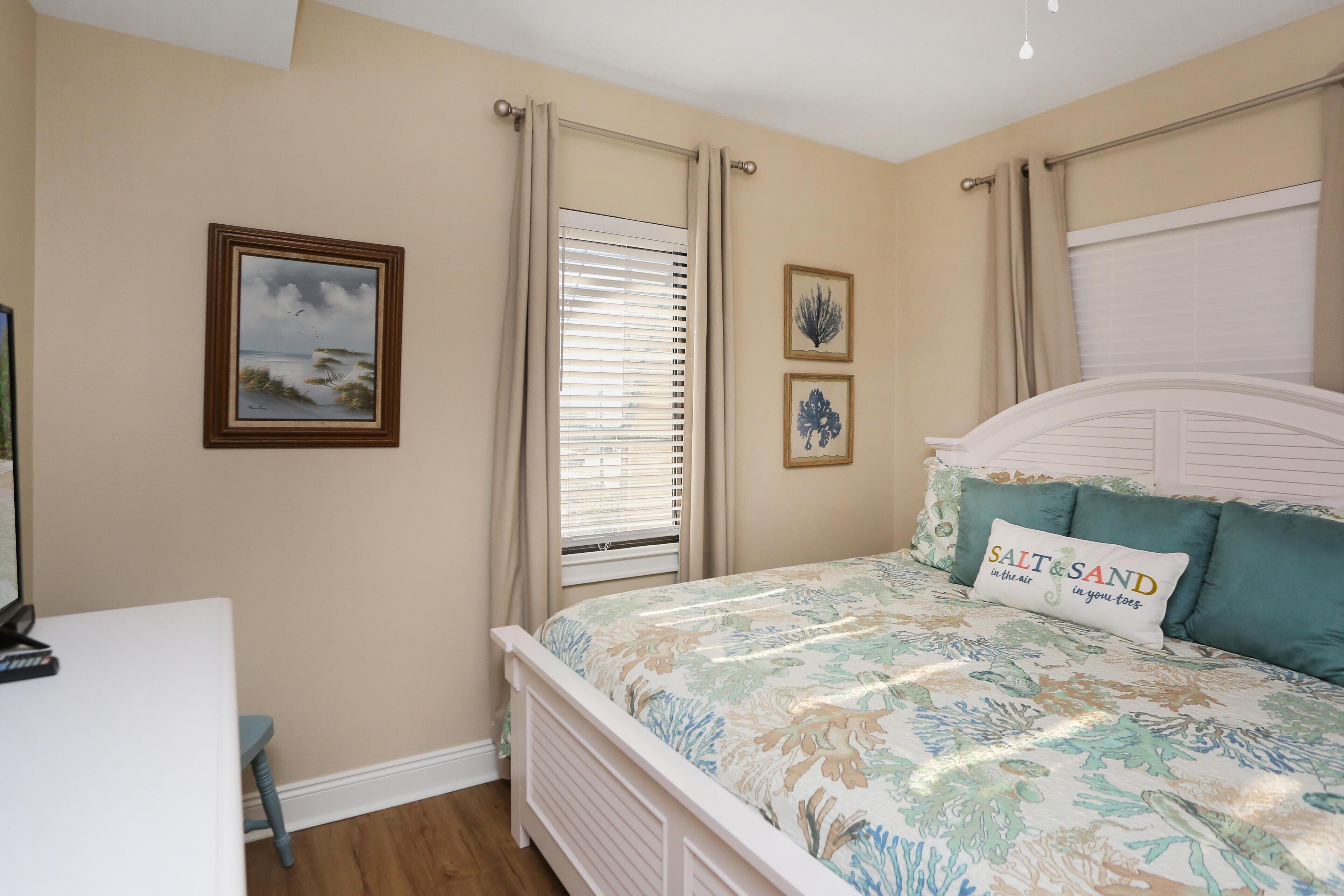 A bedroom with a bed, a desk, and a window with curtains.